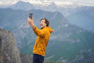 Karadağ 'daki Grlo Sokolovo vadisinin nefes kesici panoramik manzarasının arka planındaki erkek turist. Ön planda bir dağ var. Düz tarafı bir uçurum oluşturuyor. Tepe de tamamen büyümüş.