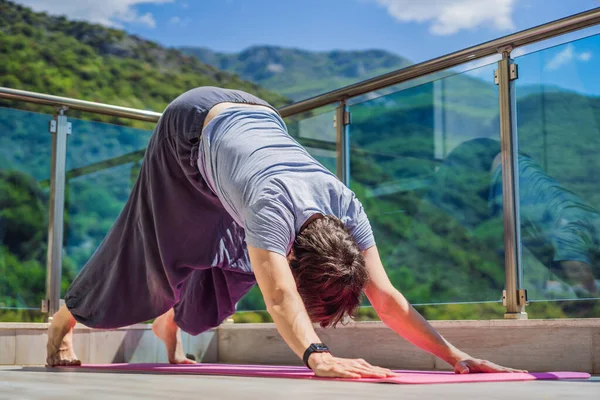 Man doing yoga outdoors on a rooftop terrace.