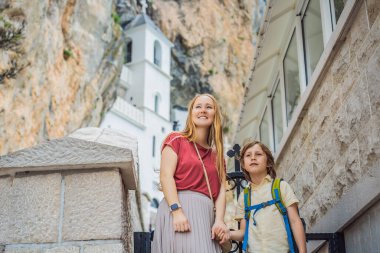 Karadağ 'ın Ostroska Greda kentindeki büyük kayanın tepesindeki Sırp Ortodoks Kilisesi' nin Ostrog Manastırı 'ndaki anne ve oğul turistler. Saint Basil 'e ithaf edilmiştir.