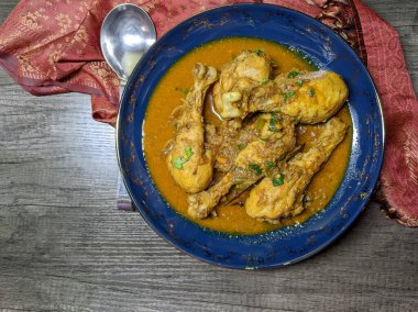 Tahta arka planda bir kase tavuk budu körisi..