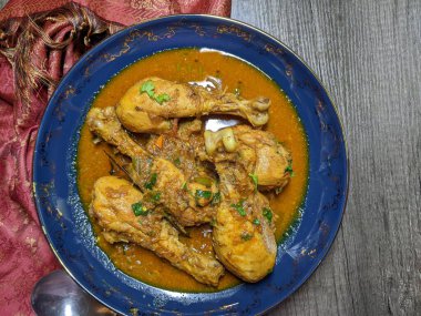 Tahta arka planda bir kase tavuk budu körisi..