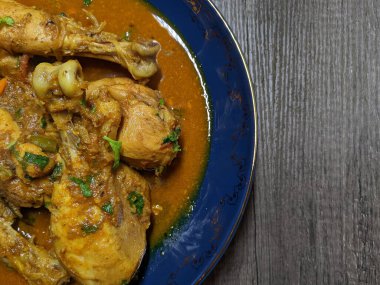 Tahta arka planda bir kase tavuk budu körisi..