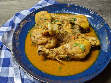 Tahta arka planda bir kase tavuk budu körisi..