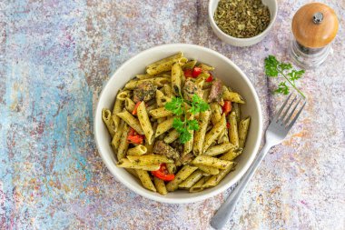Taze maydanoz yaprakları ve kurutulmuş bitkilerle süslenmiş tavuk soslu makarna.