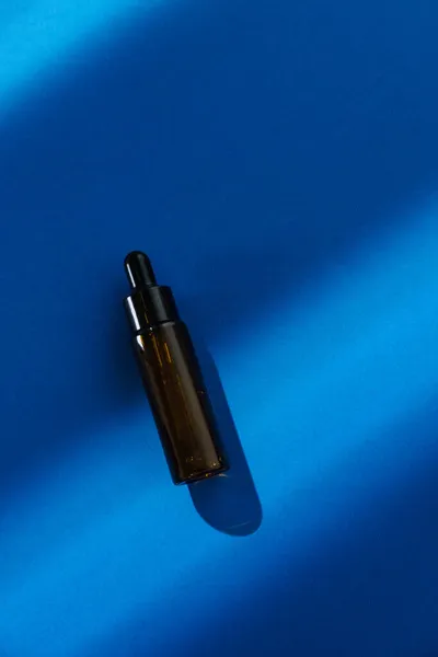蓝色底色的棕色化妆品瓶 美容品工作室摄影 静物画 简约主义概念 — 图库照片
