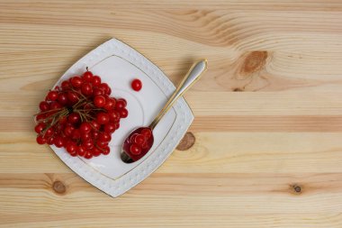 Kırmızı böğürtlenli bir grup viburnum beyaz bir tabakta. Yüksek miktarda vitamin ve sağlıklı yiyeceklerle dolu guelder gülü meyveleri..