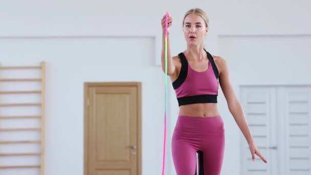 Jonge vrouwelijke turnster trainer die een lint vasthoudt en ermee speelt in een sporthal — Stockvideo