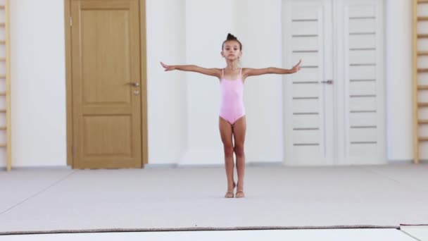 Mayolu küçük bir kız pembe stüdyoda jimnastik yapıyor. — Stok video