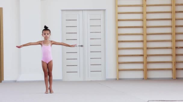 Ein kleines Mädchen im Badeanzug turnt im rosa Ballettstudio — Stockvideo