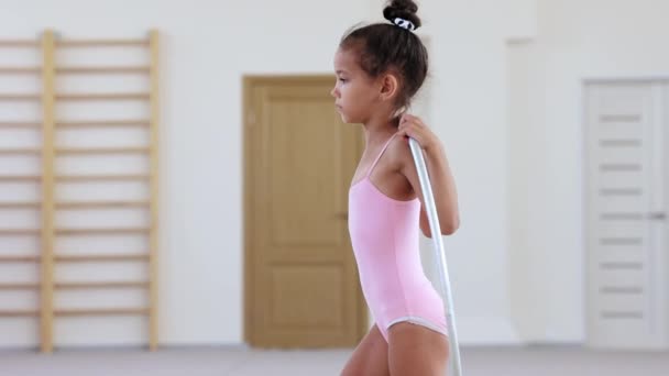 Una pequeña chica acrobática realizando un ejercicio con un aro en un estudio de ballet — Vídeos de Stock