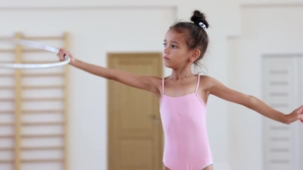 Küçük akrobatik bir kız bale stüdyosunda elinde çemberle geziyor. — Stok video