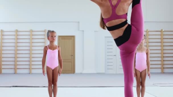 İki küçük akrobatik kız spor salonunda bayan antrenörleriyle antrenman yapıyor. — Stok video