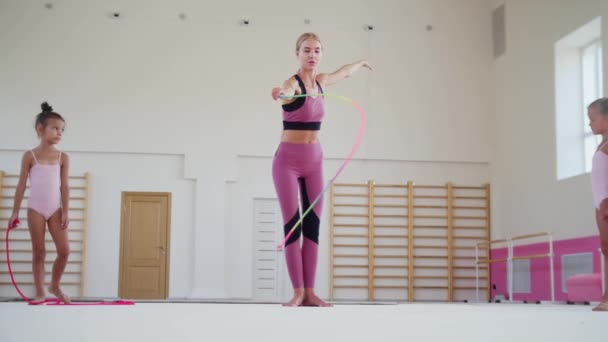 Gymnastic training - female trainer showing her two little girls students how to perform with a colorful rope — Stock Video