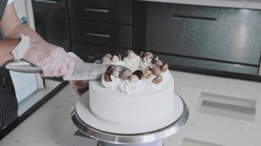 Pasta şefi yeni bir pastayı bıçakla kesiyor.
