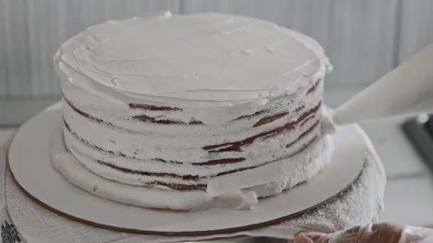 Kobieta kucharz robi ciasto - nakładanie śmietany na świeże ciasto — Wideo stockowe