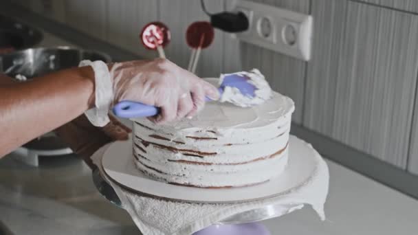 Een chef-kok maakt een taart - het aanbrengen van room op de verse taart — Stockvideo