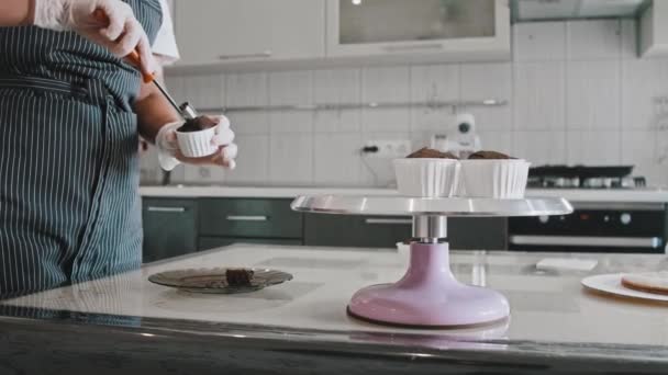 Een chef-kok die stukjes biscuit uit de cupcakes snijdt voor de komende vulling — Stockvideo