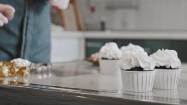 Kadın aşçı mutfakta beyaz kremayla kek süslüyor.