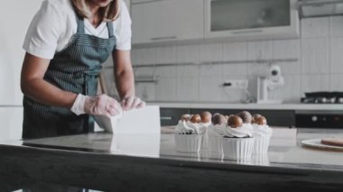 Kadın şef dekore edilmiş kekleri göndermek için karton kutu topluyor.