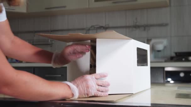 Ein Koch packt dekorierten handgemachten Kuchen in einen Karton — Stockvideo