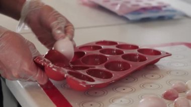 Kadın silikon formundan beyaz krema kalıpları çıkarıyor.