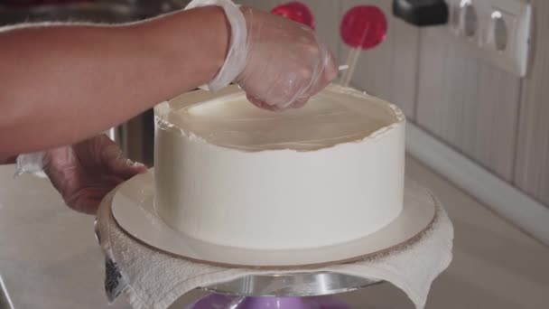 Vrouwelijke chef-kok polijsten van de crème op de top van de taart met een schouderblad — Stockvideo