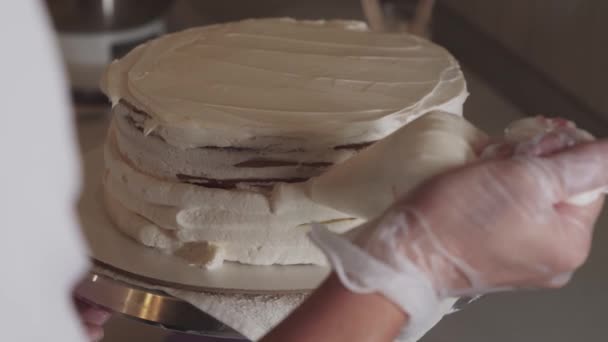 Kvinna kock täcker tårta med vit vanilj grädde med hjälp av en bageri väska — Stockvideo