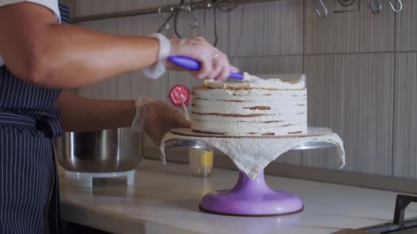 Vrouw chef smeert witte vanille crème op de top van een taart — Stockvideo