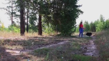 Genç bir kadın köpeğinin yakalayıp geri getirmesi için kırmızı plastik bir disk atıyor.