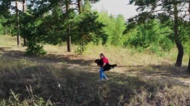 Genç, tombul bir kadın ve sevimli köpeği birlikte dışarıda oynuyorlar. Hava manzarası.