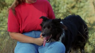 Tombul kadın ve sevimli siyah köpeği birlikte açık havada.