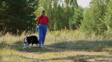 Büyük eğitimli köpek, kadın efendilerinin bacaklarının arasında yürüyor.