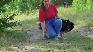 Genç tombul kadın köpeğinin yakalaması için kırmızı plastik disk atıyor.