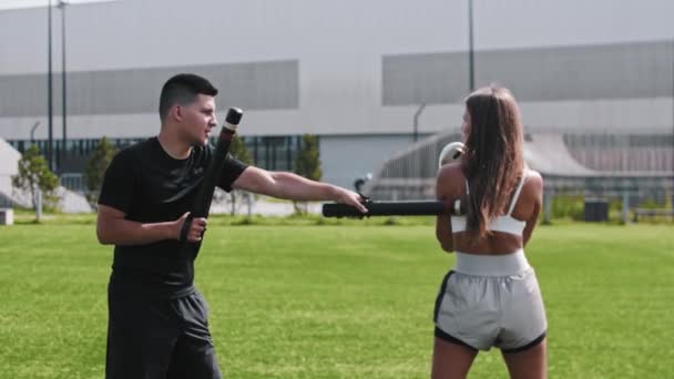 Mujer joven en entrenamiento de karate con su entrenador masculino al aire libre — Vídeos de Stock