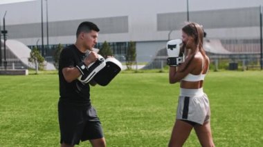 Erkek koçuyla boks eğitimi alan genç bir kadın.