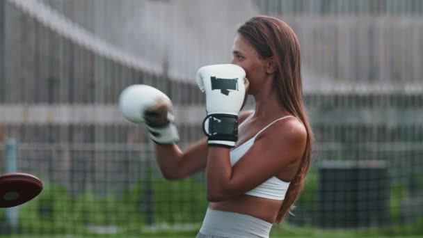 Mulher jovem em luvas de boxer que tem um treinamento - soco nos bloqueadores suaves — Vídeo de Stock