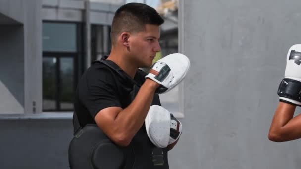 Ung kvinna som har en boxning utbildning utomhus med en manlig tränare - stansning beskyddare på hennes tränare kropp — Stockvideo