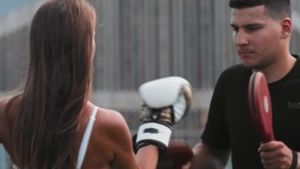 Box trénink - mladá žena mlátit rukavice na ruce svého mužského trenéra — Stock video