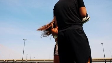 Boks antrenmanı. Boksör eldivenli genç bir kadın. Koçunun ellerinde hedefi tekmeliyor.