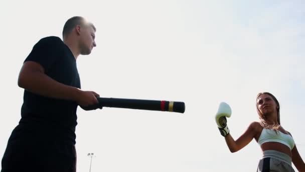 Boxing training outdoors - young woman training the kick on the target in her coaches hand — Stock Video