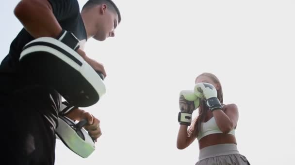 Boxing training - young woman kicking the mitt with her knee on her coaches hand — Stock Video
