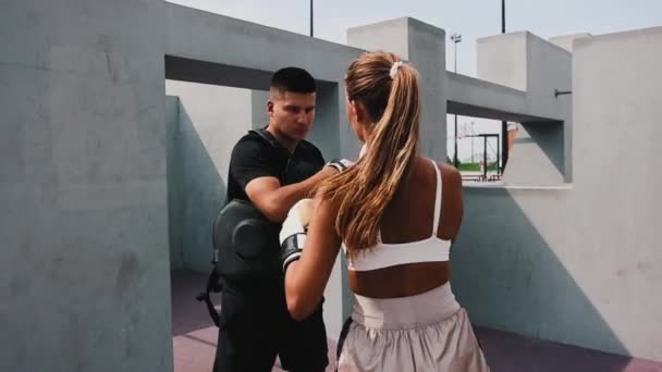 Bokstraining op de bouwplaats - jonge vrouw met haar haar in paardenstaart die haar stoten traint met een coach — Stockvideo