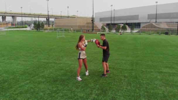 Mujer joven en un entrenamiento de boxeo en el campo de fútbol con su entrenador masculino — Vídeo de stock