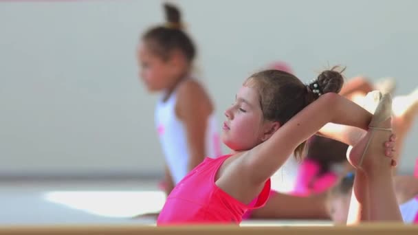 KAZAN, RUSIA 24-08-21: niña en entrenamiento de vestuario rosa en clase de gimnasia en el pabellón deportivo estirando la espalda — Vídeos de Stock