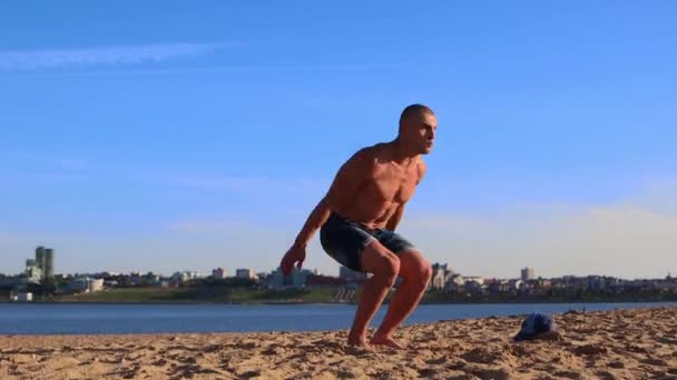 Junger fitter Mann macht Liegestütze auf dem Sand am Strand und macht Saltos — Stockvideo