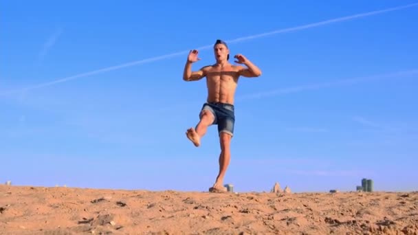 Junger fitter Mann macht Sport am Strand - hockt auf einem Bein — Stockvideo