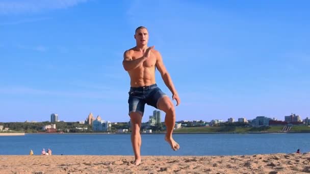 Νεαρός κάνει αθλητικές ασκήσεις στην παραλία, ενώ ηλιόλουστη μέρα του καλοκαιριού — Αρχείο Βίντεο