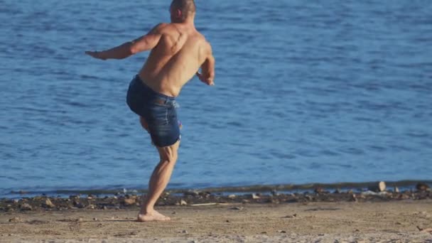 Ejercicios deportivos al aire libre: hombre joven en forma realizando movimientos de lucha en la playa — Vídeos de Stock