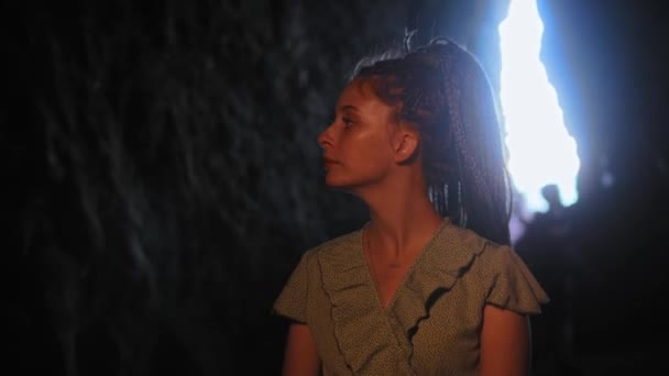 Viaje de aventura - mujer joven de pie en una cueva oscura y mirando a su alrededor — Vídeo de stock