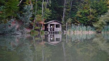 Macera gezisi - genç bayan turist gölün yanındaki küçük tahta evde duruyor.